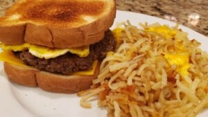 sausage egg and cheese sandwich in toast with hashbrowns and cheese