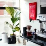 red and silver coffee maker beside white ceramic mug