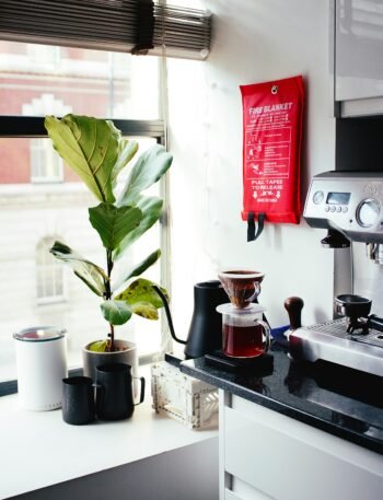 red and silver coffee maker beside white ceramic mug