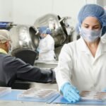 three people inside factory wearing masks and coats