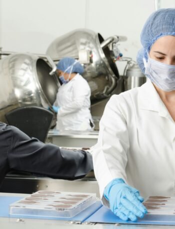 three people inside factory wearing masks and coats