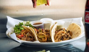 a plate of tacos with a lime being drizzled on top