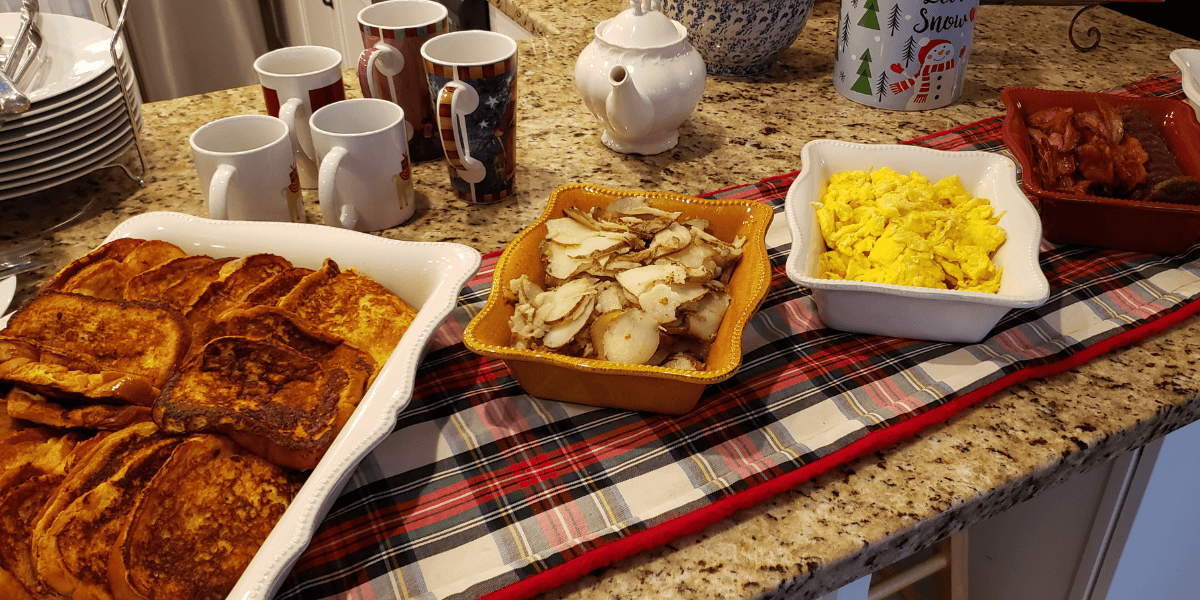 Crispy French toast with syrup, breakfast casserole, scrambled eggs, roasted potatoes, hearty holiday breakfast.