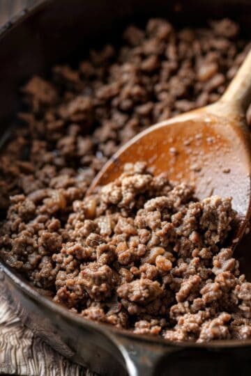Ground beef cooking in a skillet with a wooden spoon, perfect for meal prep and recipes.