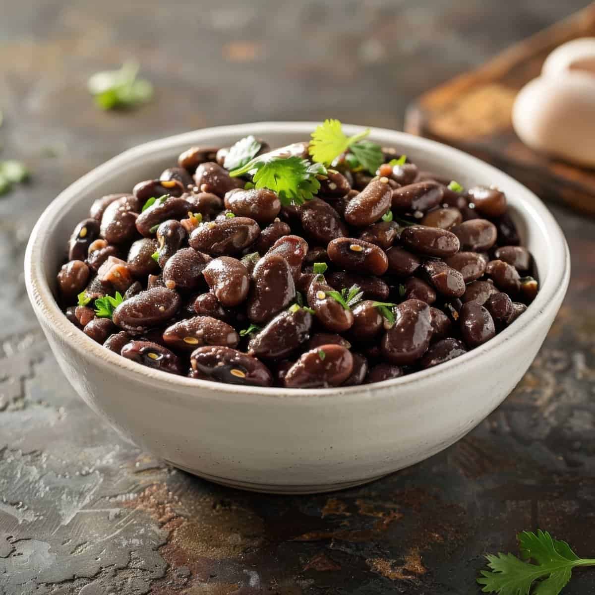 Black beans in a white bowl with cilantro garnish, perfect for healthy meals.