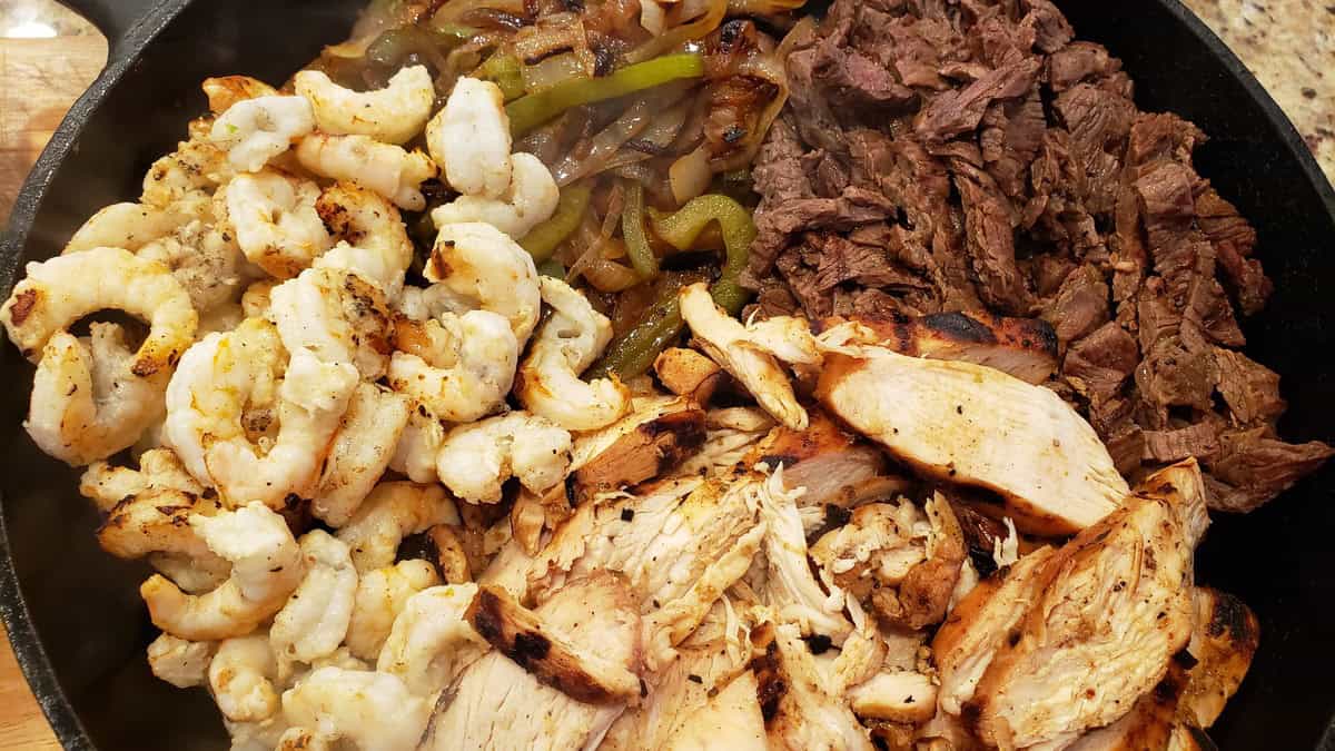 Delicious grilled shrimp, chicken, and beef served on a skillet, perfect for a hearty meal.